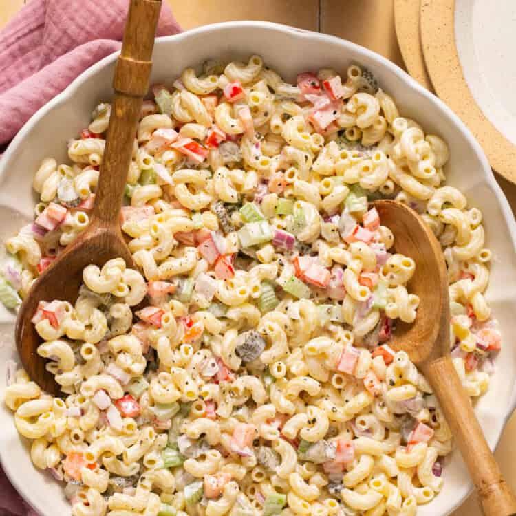 Healthy macaroni salad (deli style) in a large bowl with a wooden spoon.