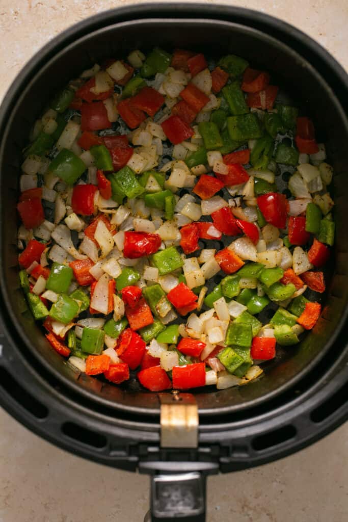Chopped peppers and onions in an air fryer.