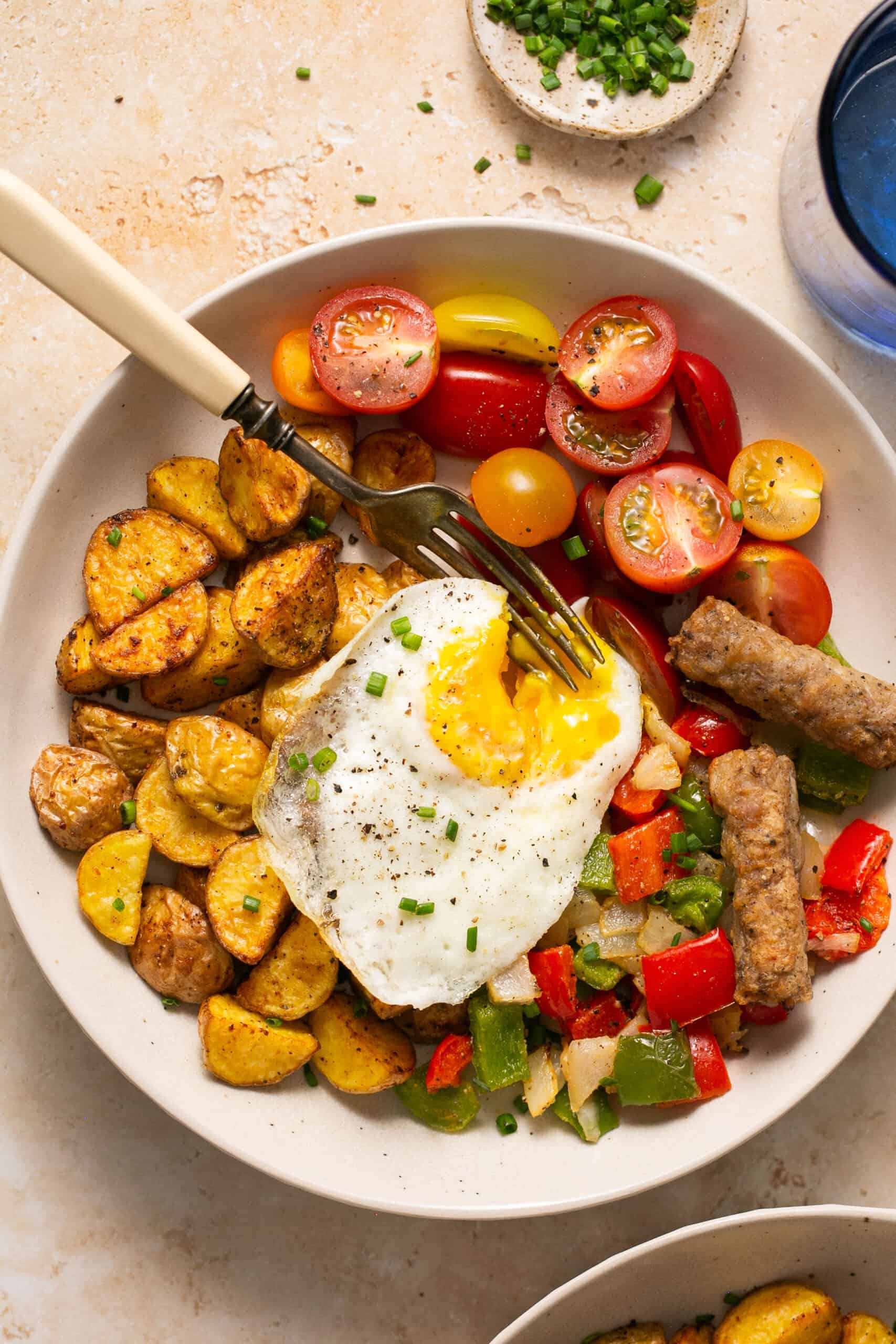 Healthy breakfast bowls with eggs and potatoes in a bowl with a fork.