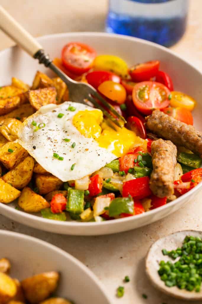 Zoomed in view of healthy breakfast bowls with eggs and potatoes in a bowl with a fork.