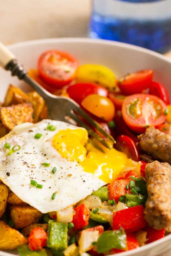 Zoomed in view of healthy breakfast bowl with eggs and potatoes in a bowl with a fork.