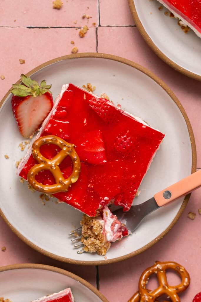 Piece of low sugar healthy strawberry pretzel salad on plate with fork.