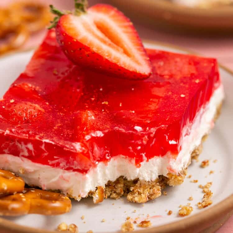 Low sugar strawberry pretzel salad topped with a strawberry on a small plate.