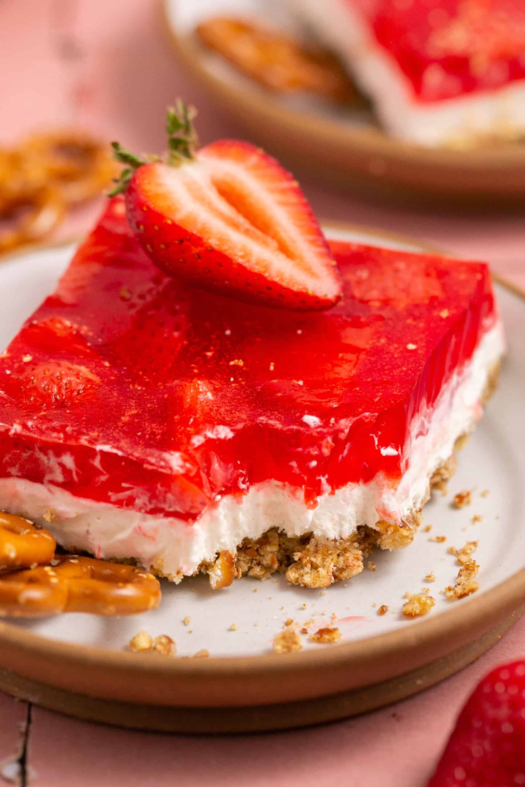 Low sugar strawberry pretzel salad topped with a strawberry on a small plate.