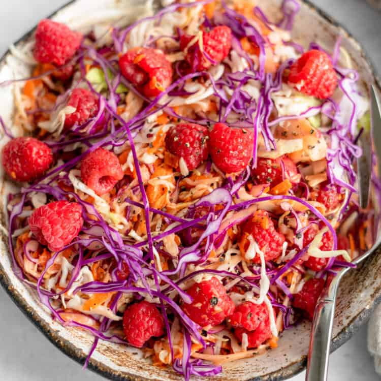 Ruby Red Raspberry Coleslaw in bowl with serving spoon.