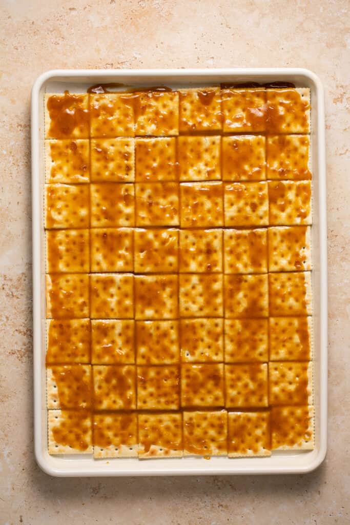 Toffee poured over the layer of crackers on a baking sheet.