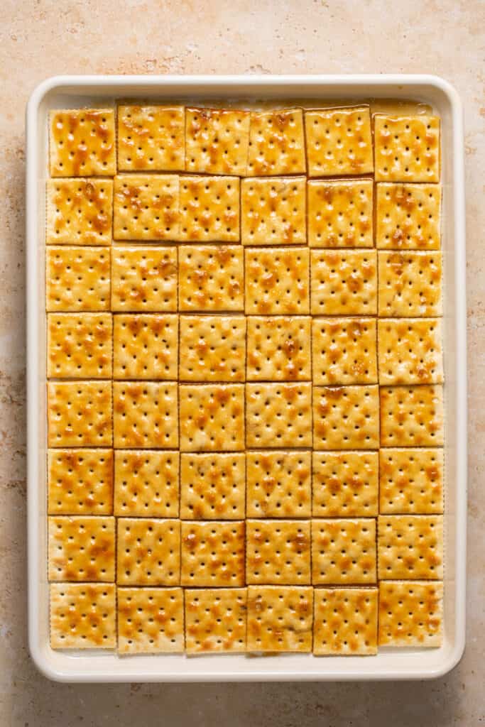 Crackers topped with toffee on a baking sheet.