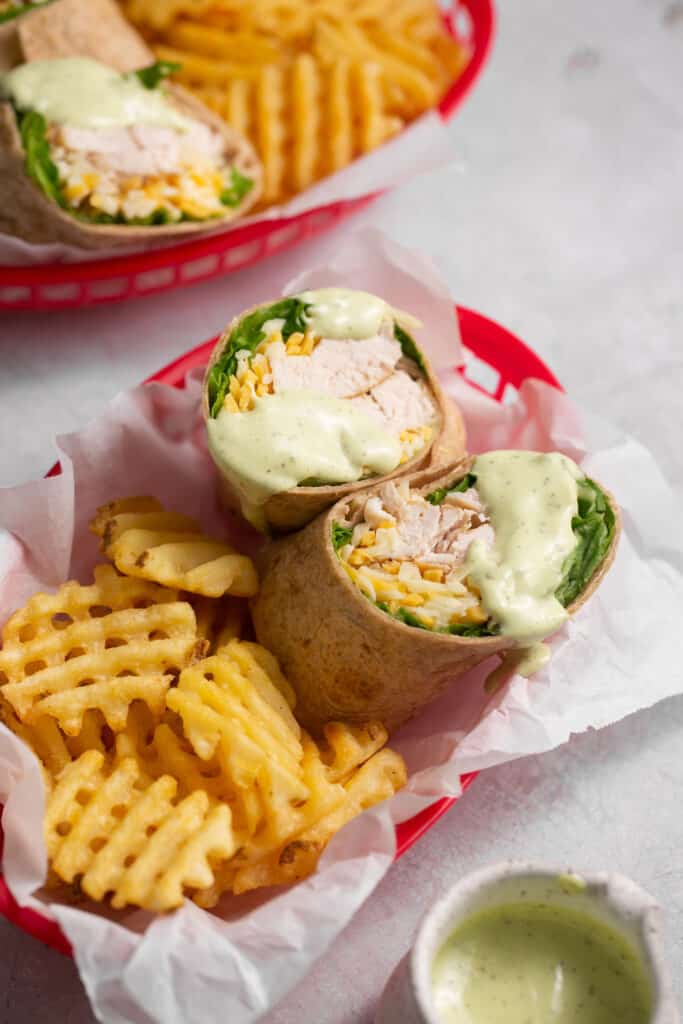 Chick fil a grilled chicken cool wrap cut in half in a basket with a side of waffle fries.