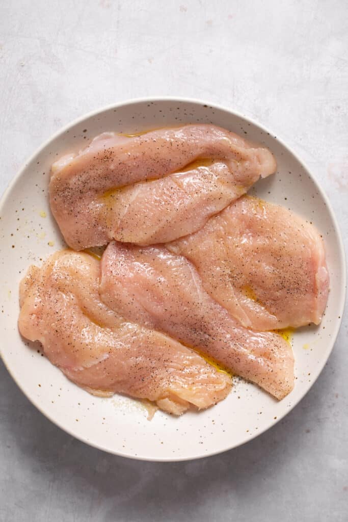 Raw chicken breasts on a plate.