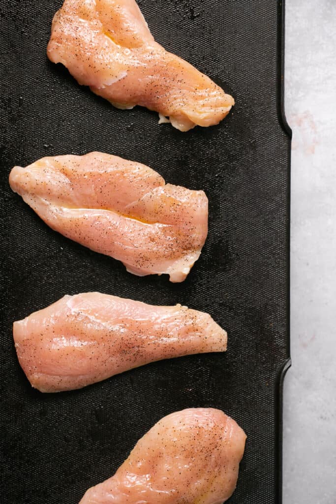 Raw chick breasts on a grill.