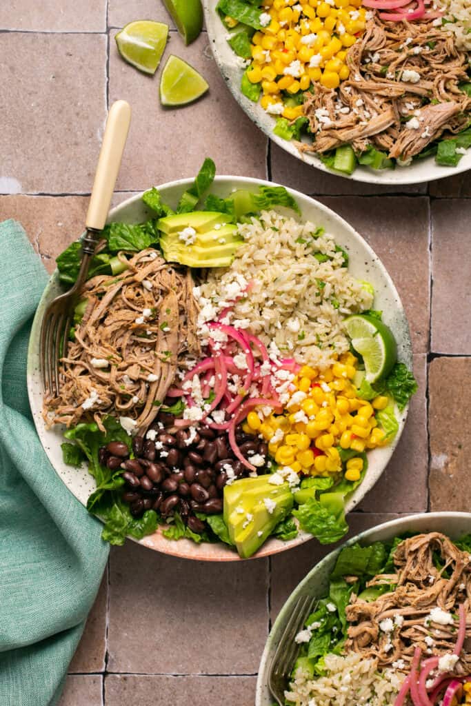 Carnitas burrito bowls in bowls with forks.
