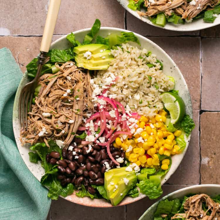 Carnitas burrito bowls in bowls with forks.