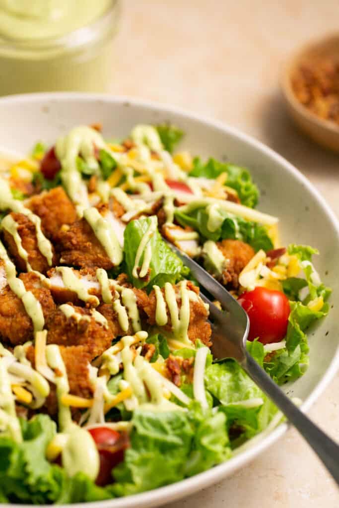 Zoomed with view of chick-fil-a cobb salad recipe topped with avocado lime dressing in a bowl with a fork.