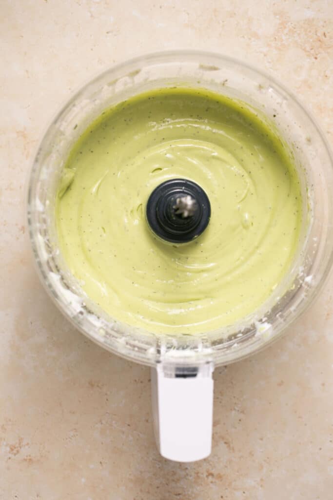 Avocado lime ranch dressing in a food processor after being blended up.