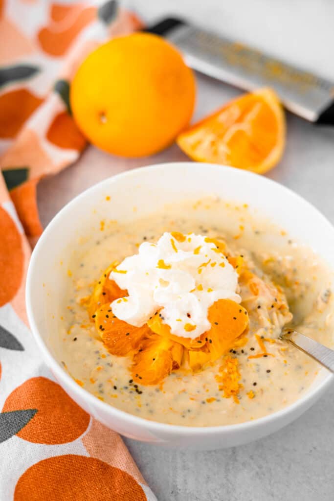 Orange Creamsicle Overnight Oats in white bowl with spoon.