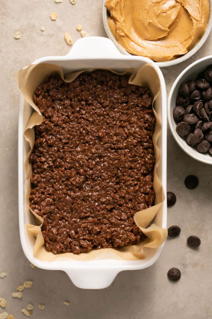 Chocolate peanut butter crunch bars in a baking dish with parchment paper.