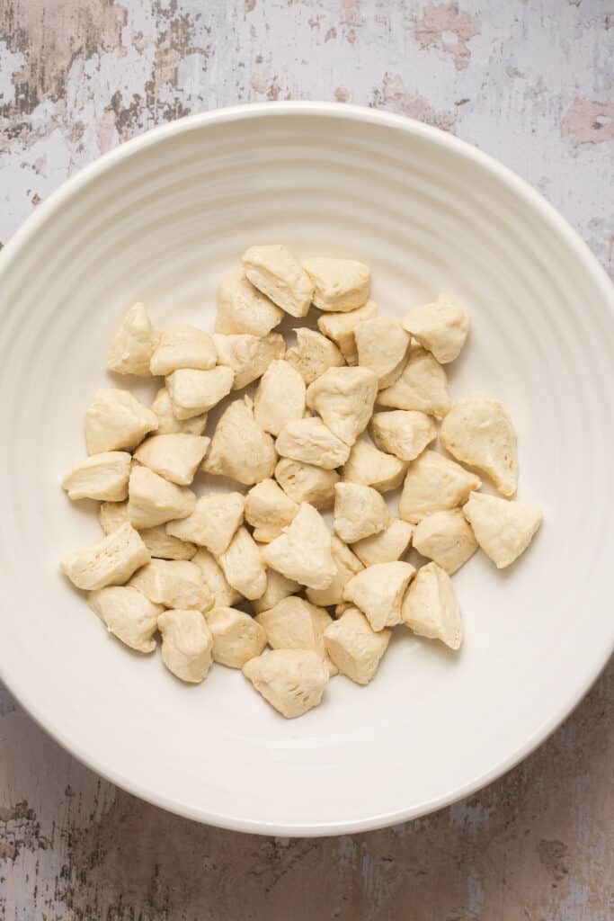 Uncooked biscuits cut into pieces in a bowl.