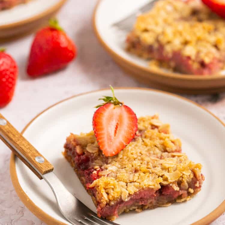 Healthy strawberry crumble bars topped with strawberry slices on a plate with a fork.