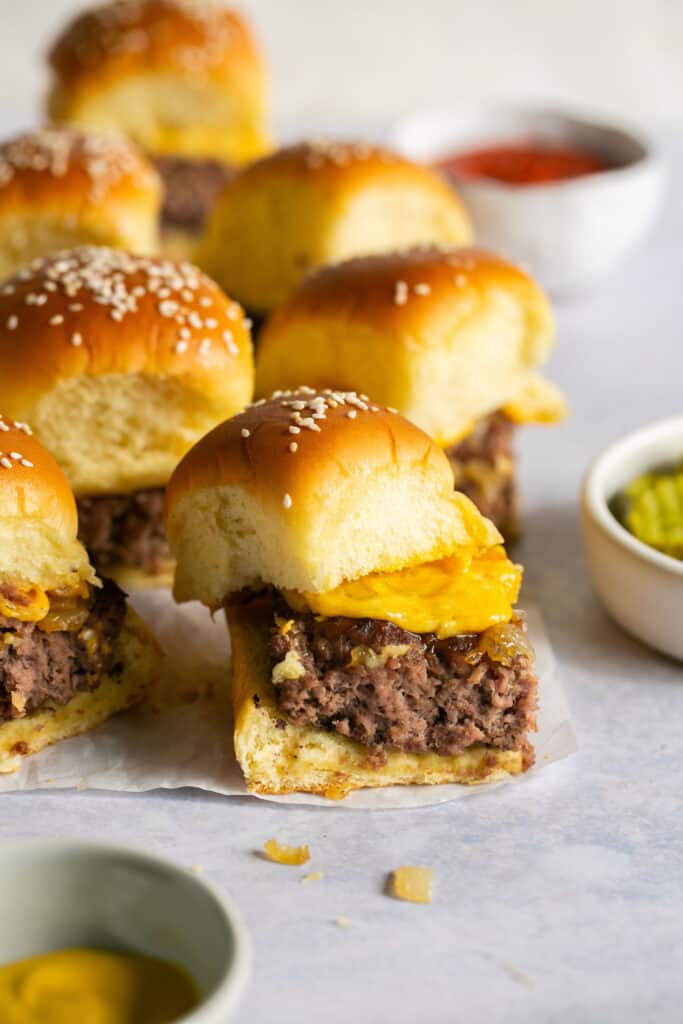 Cheeseburger sliders with hawaiian rolls on parchment paper.