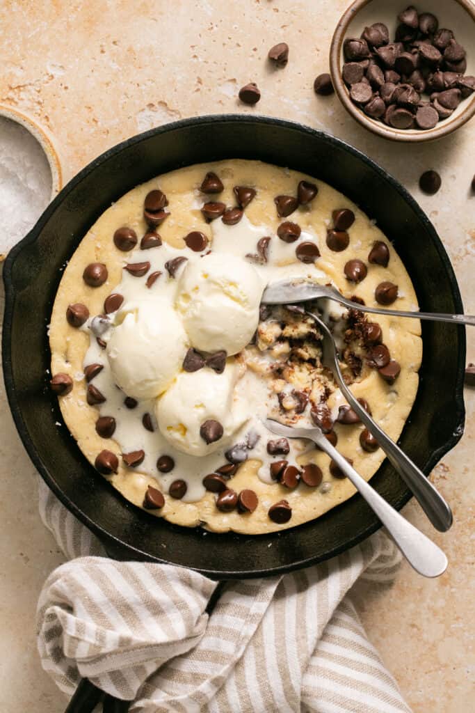 Protein skillet cookie topped with ice cream and spoons in a skillet.