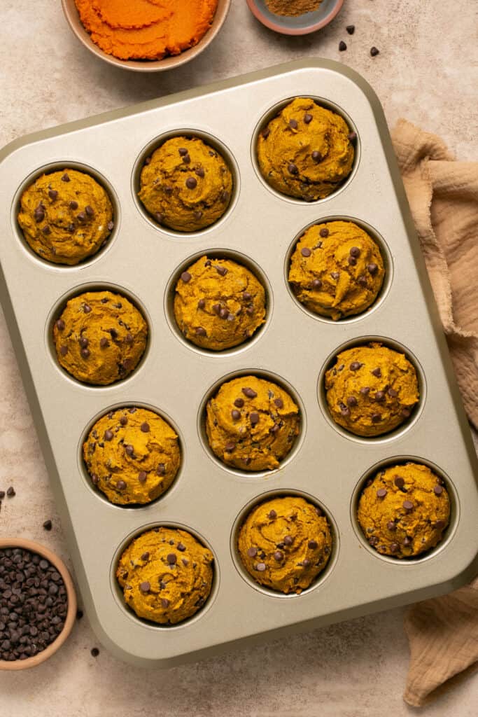 Healthy chocolate chip pumpkin muffins in a muffin pan after being baked.