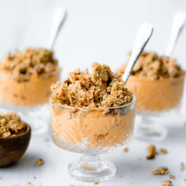 Pumpkin mousse with pecan crumble in a bowl with a spoon.