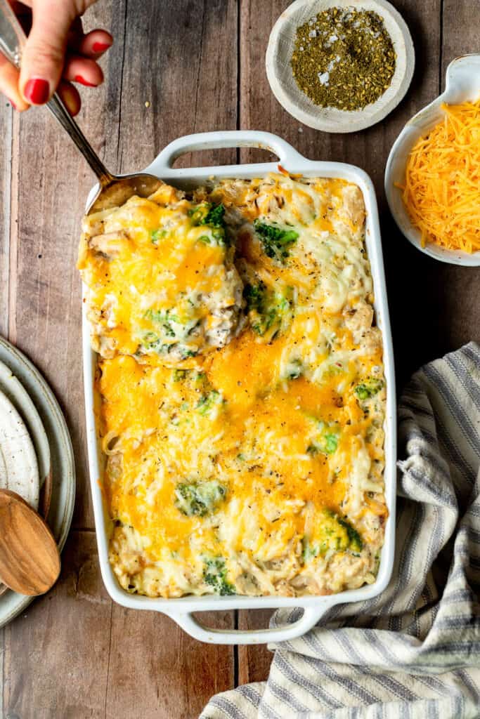 Chicken broccoli hashbrown casserole in a baking dish, some being served with a spoon.