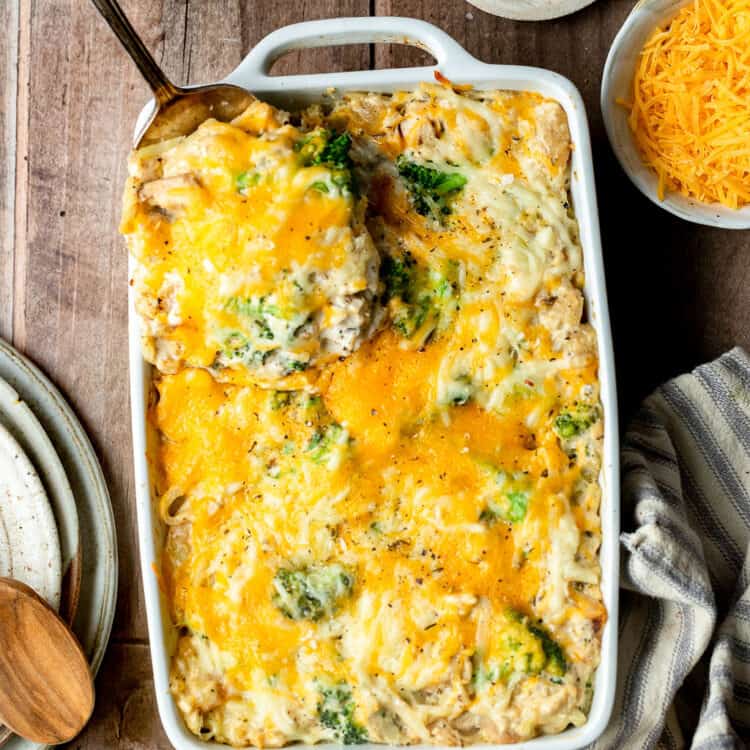 Chicken broccoli hashbrown casserole in a baking dish, some being served with a spoon.