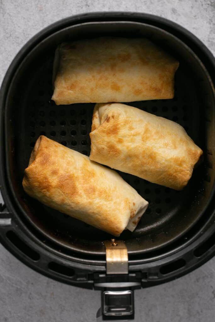 Buffalo chicken ranch wrap in an air fryer basket after being cooked.