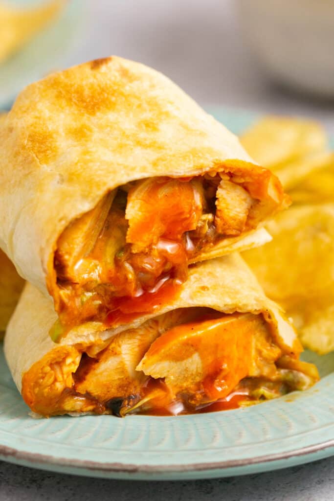 Air fryer buffalo chicken wrap cut in half and stacked on top of each other on a plate.
