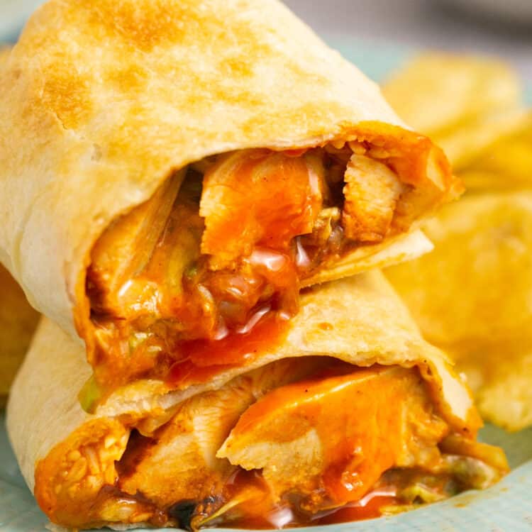 Air fryer buffalo chicken wrap cut in half and stacked on top of each other on a plate.
