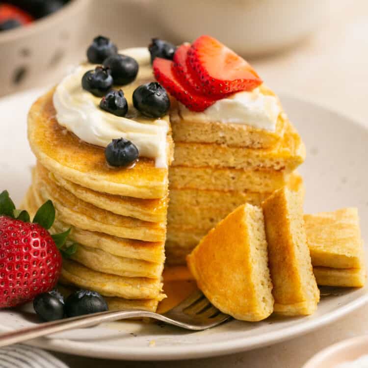 Protein powder Pancakes topped with greek yogurt and berries on a small plate with a fork.