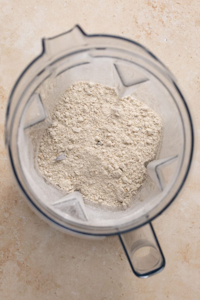 Dry ingredients in the bowl of a food processor after being mixed together.