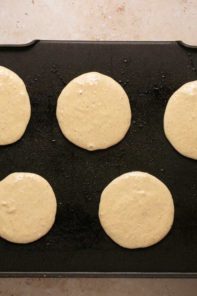 Pancakes on a griddle being cooked.