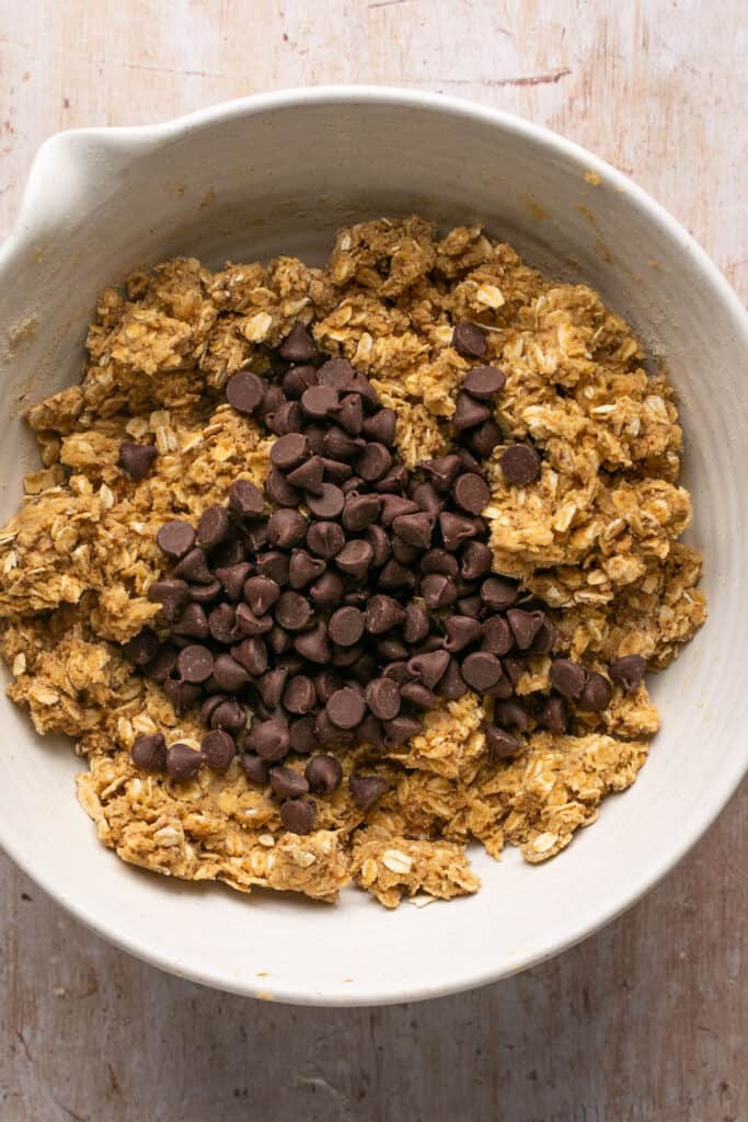 Chocolate chips added to the ingredients in a mixing bowl.