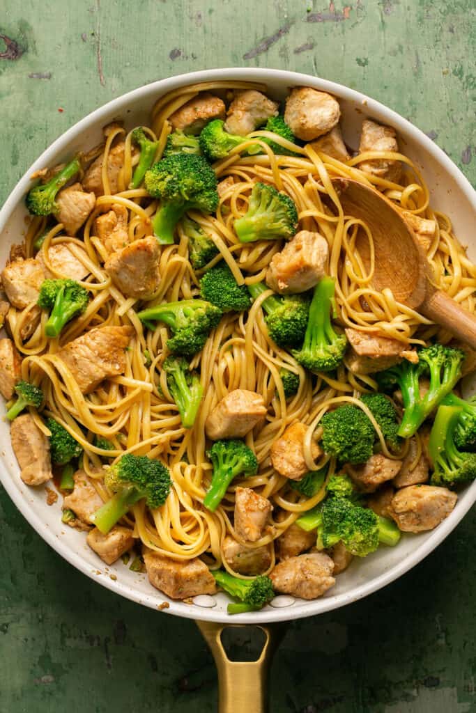 Sesame noodles with chicken and broccoli in a skillet.