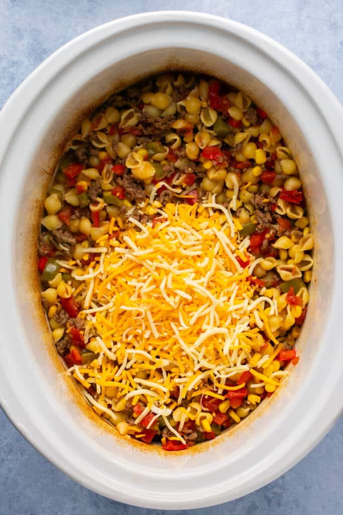 Crockpot taco pasta topped with shredded cheese in a crock pot.