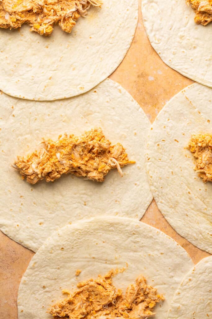 Chicken and cheese mixture placed on tortillas before being wrapped.