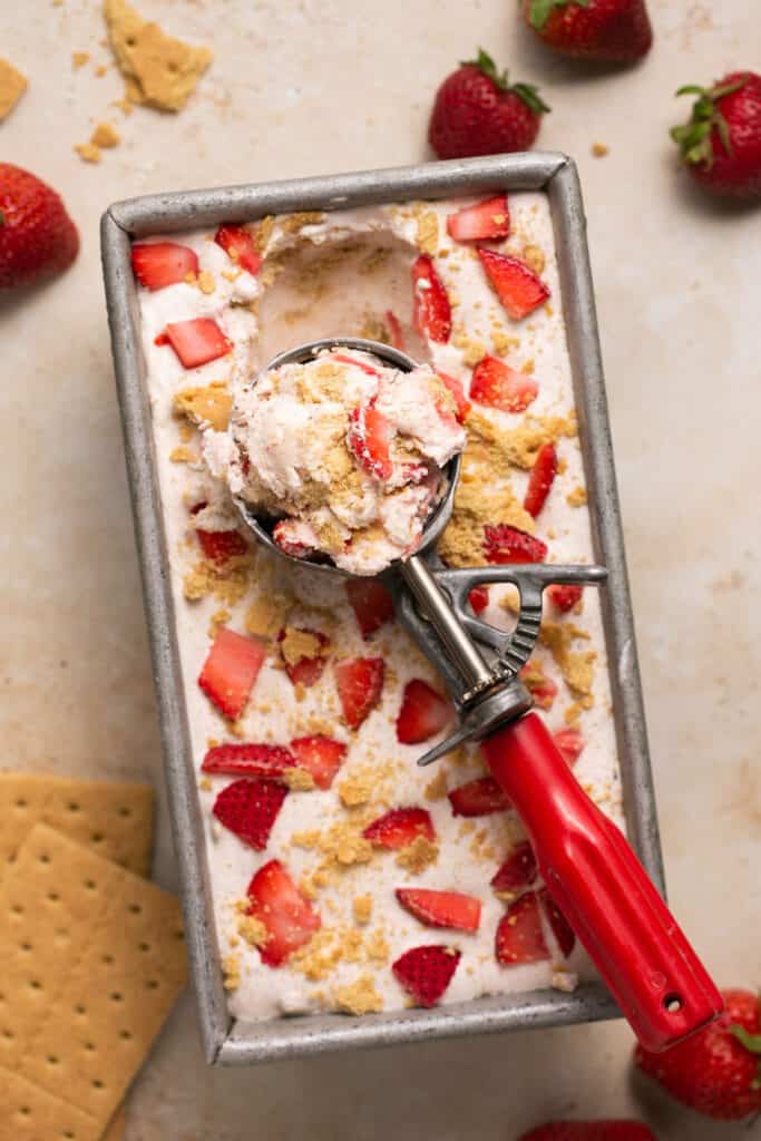 Strawberry cheesecake ninja creami protein ice cream in a container with an ice cream scoop.