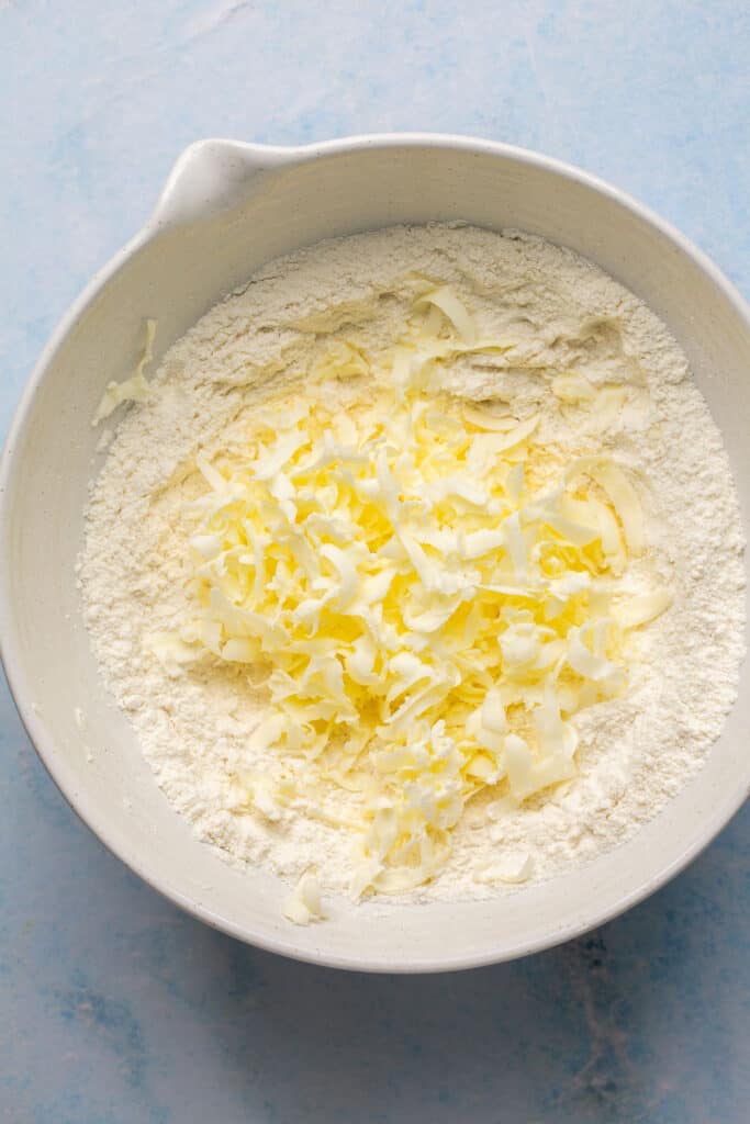 Butter added to the dry ingredients in a mixing bowl.