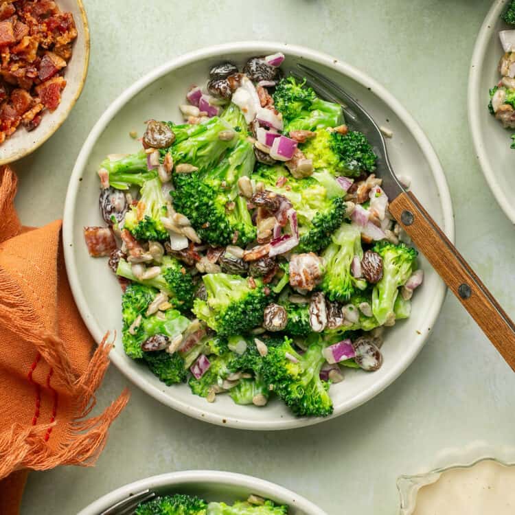 Healthy broccoli salad with greek yogurt on a plate with a wooden spoon.