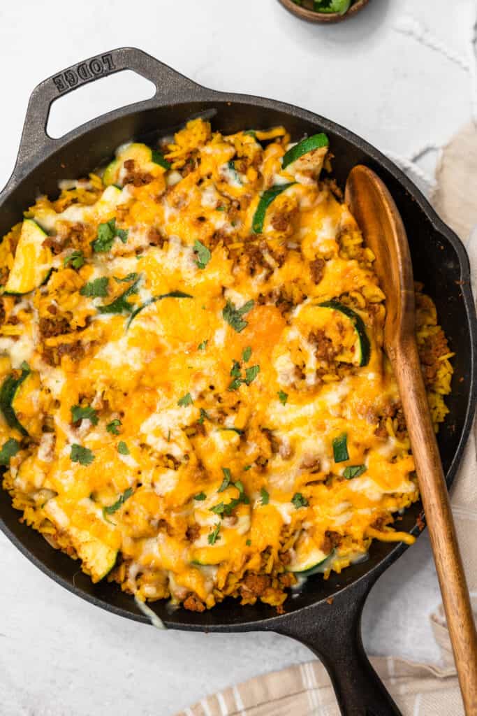 Yellow rice and ground turkey skillet with a wooden spoon.