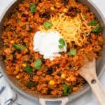 Sazon quinoa ground turkey skillet topped with sour cream and shredded cheese.