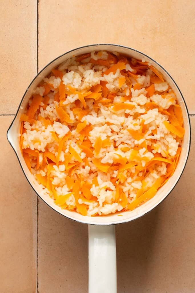 Cooked rice and shredded carrots in a saucepan.