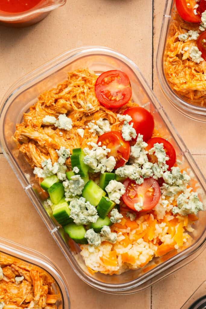 Buffalo chicken rice bowls in meal prep containers.