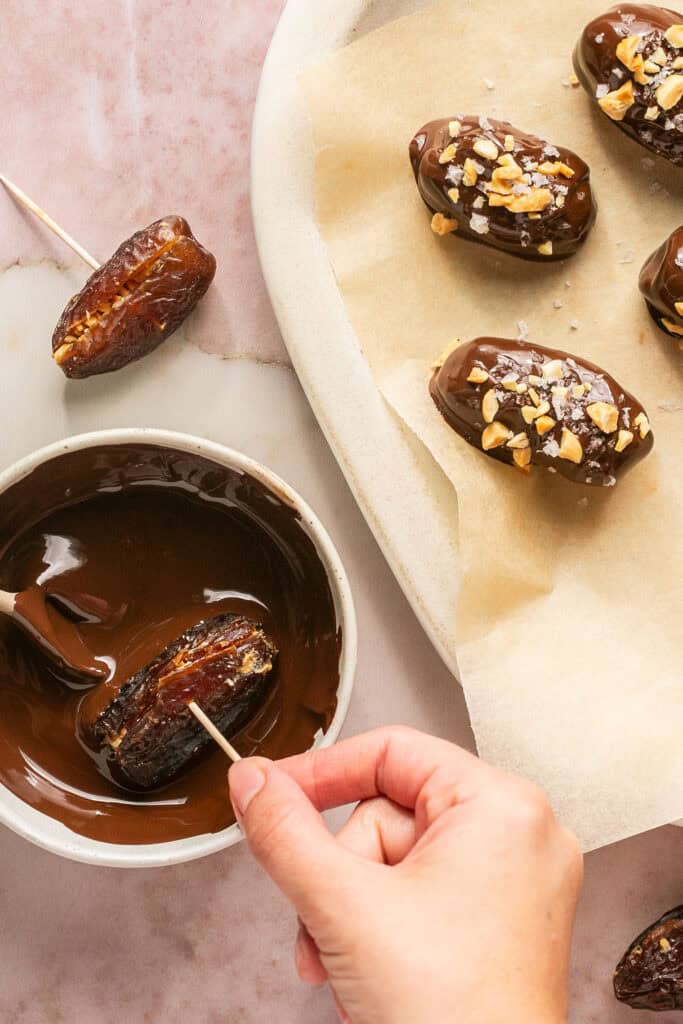 Stuffed dates being dipped in melted chocolate chips.