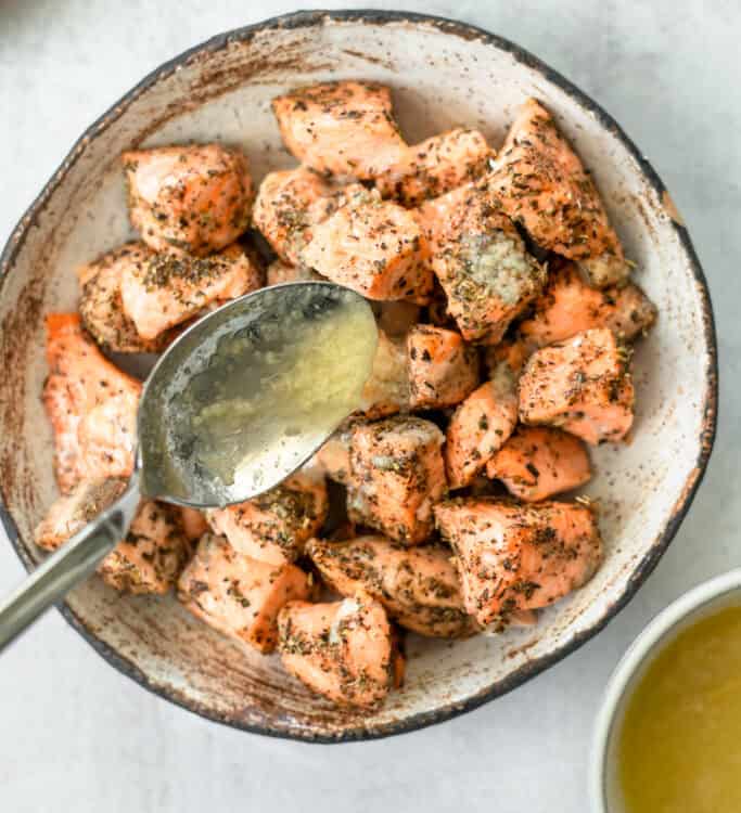 Lemon butter salmon bites in a bowl with a spoon.