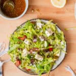 Chopped greek salad in a bowl with dressing on the side.