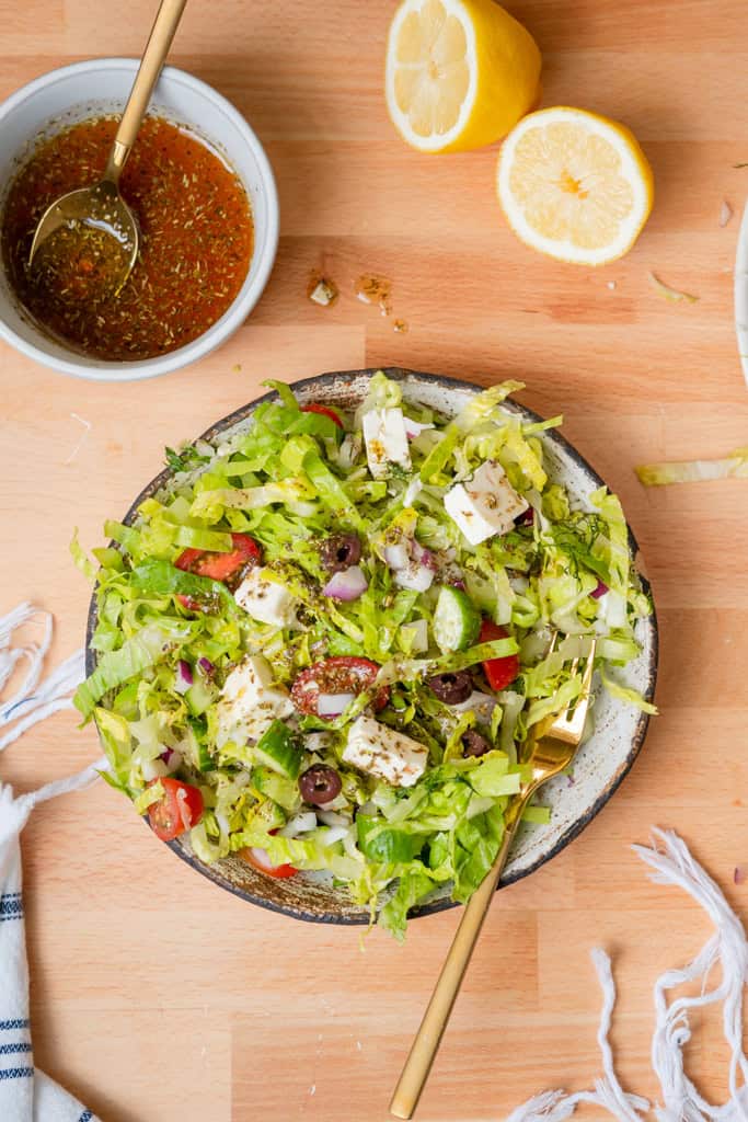 Chopped greek salad in a bowl with dressing on the side.