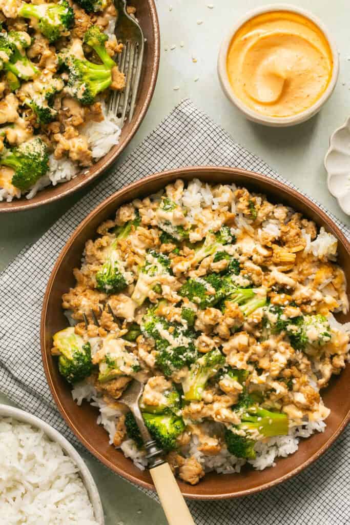 Asian ground chicken rice bowls with a fork and side of sriracha mayo.